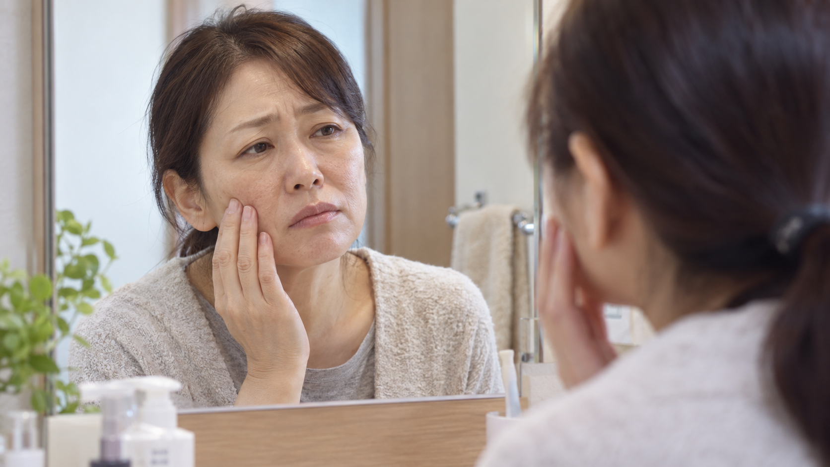 鏡で自分の荒れた肌を見てガッカリする50代女性
